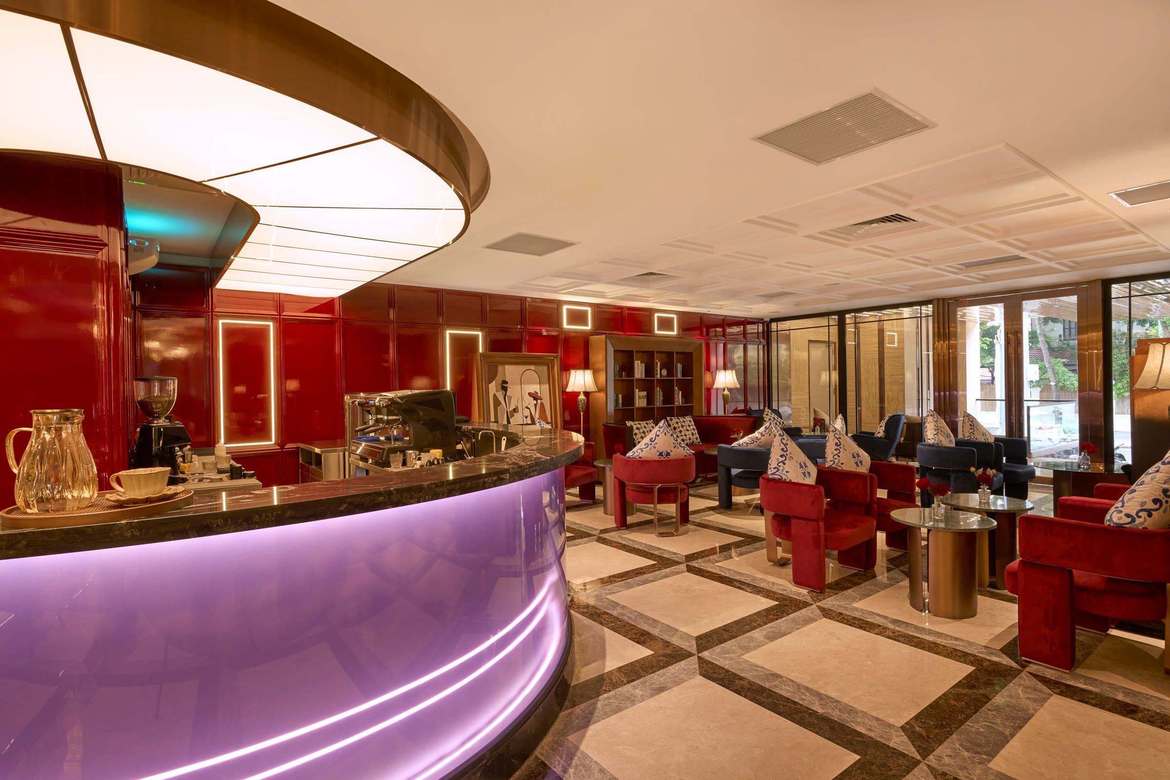 A barista smiles behind the curved bar, red lacquer panels and a curved ceiling light behind.