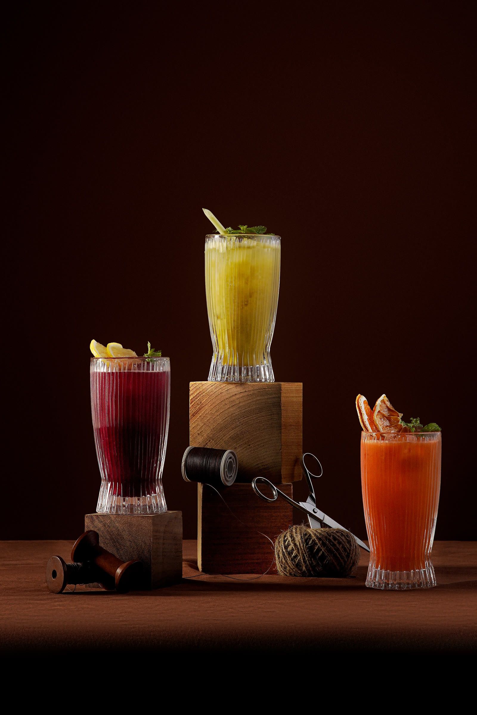 Three tall glasses of juice in ruby red, yellow and orange.